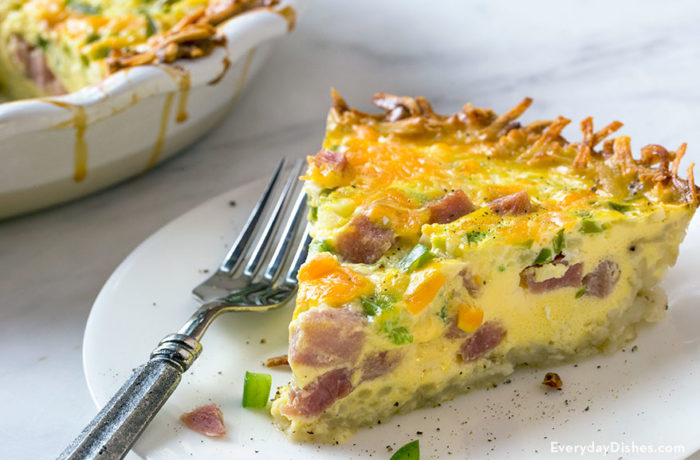 A slice of hash brown quiche with ham, on a plate and ready to eat.