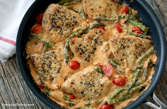 Rich and savory one-pan chicken with spring vegetables, in a skillet and ready to serve for dinner.