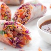 Some freshly made sesame spring rolls next to a bowl of dipping sauce