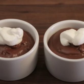 Two cups of homemade chocolate pudding, topped with a dollop of whipped cream.