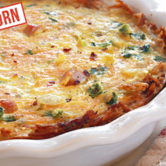 A baking dish with an einkorn hash brown quiche with ham, ready to enjoy.