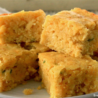 A plate of spicy homemade cornbread, cut up and ready to serve.