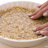 An almond pie crust being pressed into the pan.