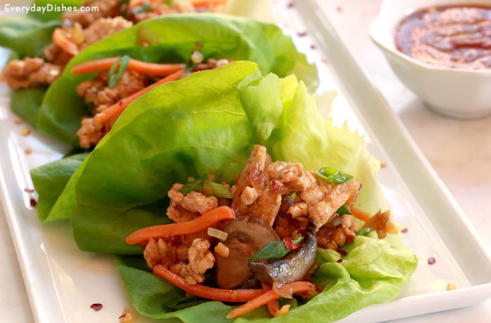 A plate of chicken lettuce wraps with peanut sauce.
