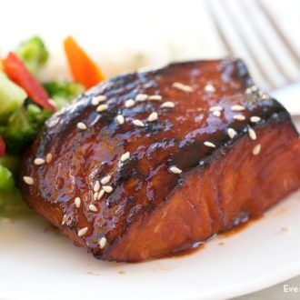 A piece of a delicious broiled sriracha salmon with a side of veggies.