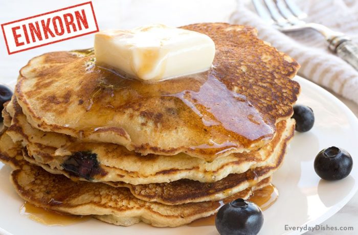 A stack of overnight einkorn blueberry pancakes, topped with butter and syrup — the perfect premade breakfast!