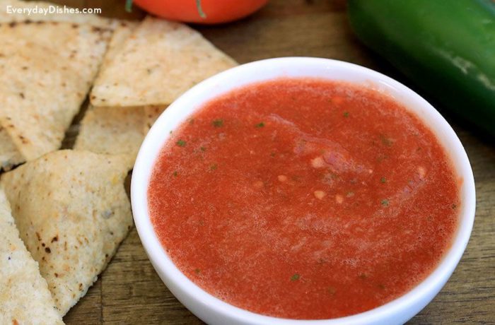 A bowl of spicy homemade salsa with a side of chips.
