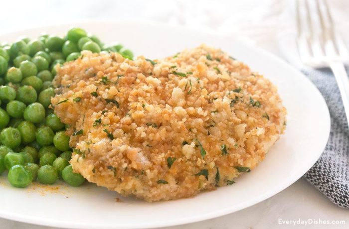 A butter baked chicken breast with a side of peas. A healthy and tasty dinner.