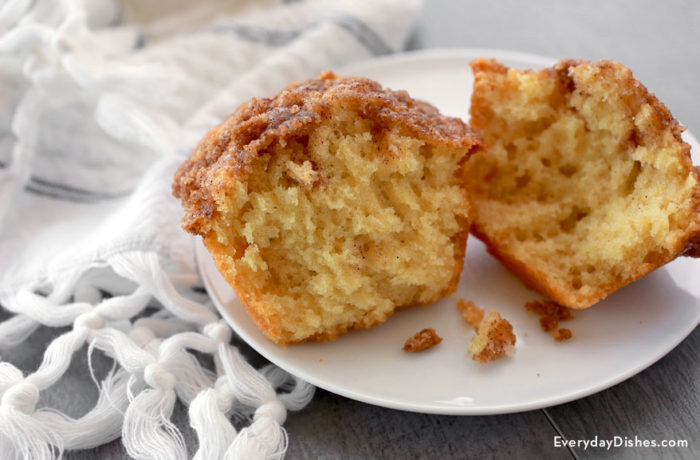 A cinnamon streusel muffin, cut in half and sitting on a plate.