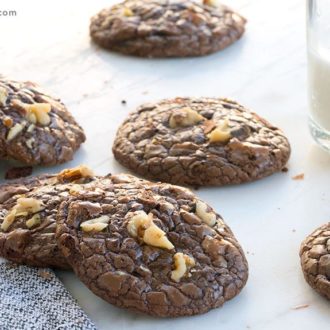 A fresh batch of dark chocolate walnut cookies, with a glass of milk.
