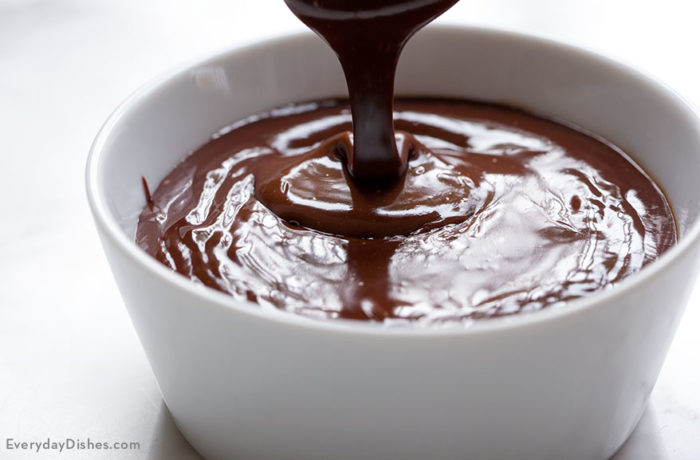 Homemade chocolate ganache being drizzled into a bowl.
