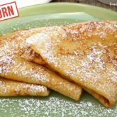 A plate with three Einkorn crepes with powdered sugar sprinkled on them.