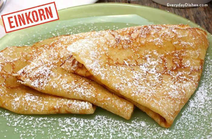 A plate with three Einkorn crepes with powdered sugar sprinkled on them.