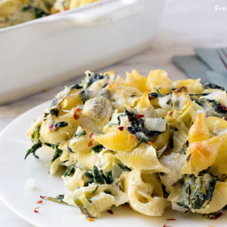 A plate with a serving of spinach artichoke pasta casserole.