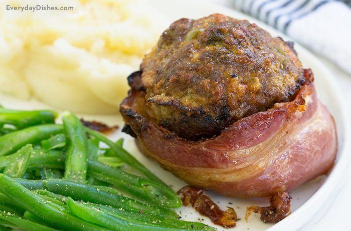 A bacon-wrapped mini meatloaf cup on a plate with mashed potatoes and green beans