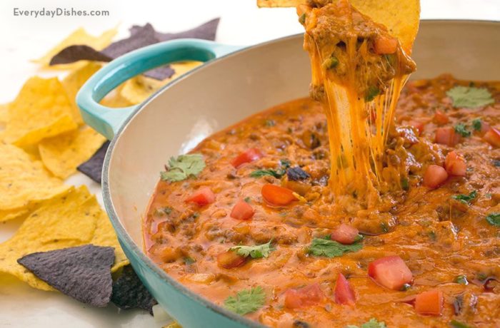 A bowl of a tasty chorizo fundido queso dip, served with chips.