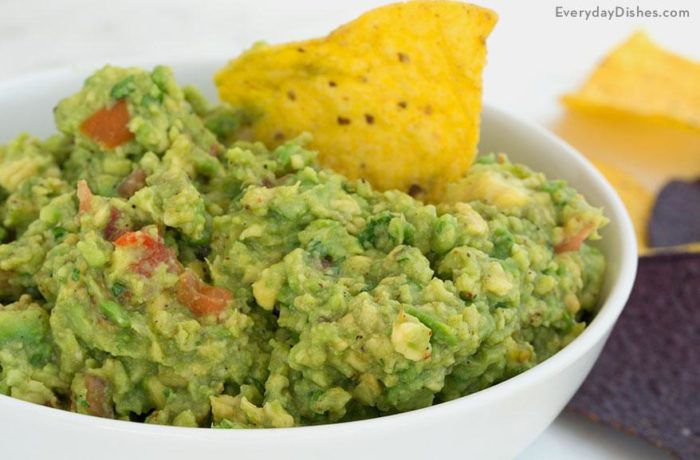 A bowl of homemade guacamole with a chip in it.