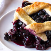 A piece of a delicious blueberry slab pie with a lattice crust.