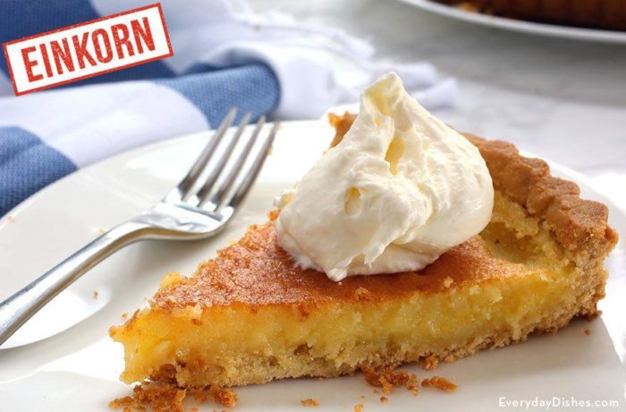 A slice of einkorn lemon tart, topped with a dollop of whipped cream