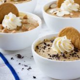 Bowls of homemade butterscotch pudding, topped with whipped cream, a cookie, and other garnishments.