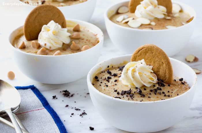 Bowls of homemade butterscotch pudding, topped with whipped cream, a cookie, and other garnishments.