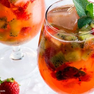 Two glasses of a kiwi strawberry cocktail, garnished with mint.