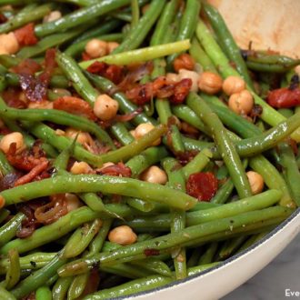 A skillet full of bacon-braised green beans and chickpeas.