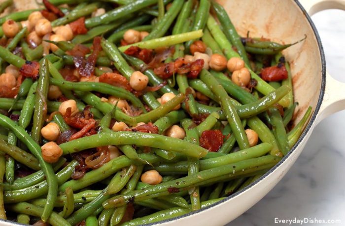 A skillet full of bacon-braised green beans and chickpeas.