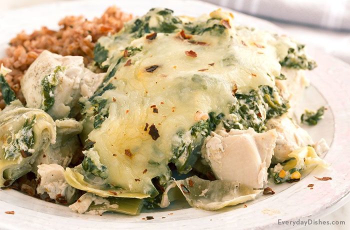 A plate with a serving of baked chicken and spinach with artichoke, the perfect dinner.