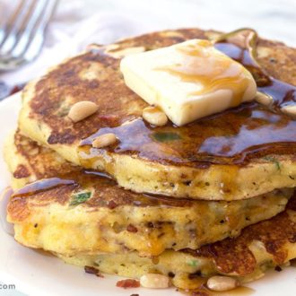 A stack of green chili pancakes with butter and syrup, a sweet and zesty start to the day.