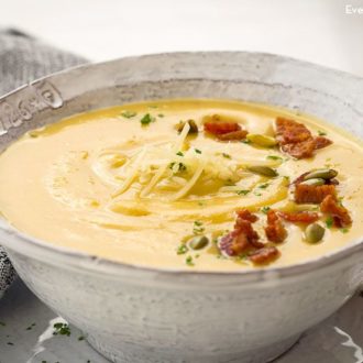 A bowl of roasted acorn squash soup with bacon and pumpkin seeds