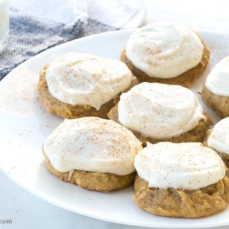 A plate of pumpkin cookies, iced with cream cheese frosting.
