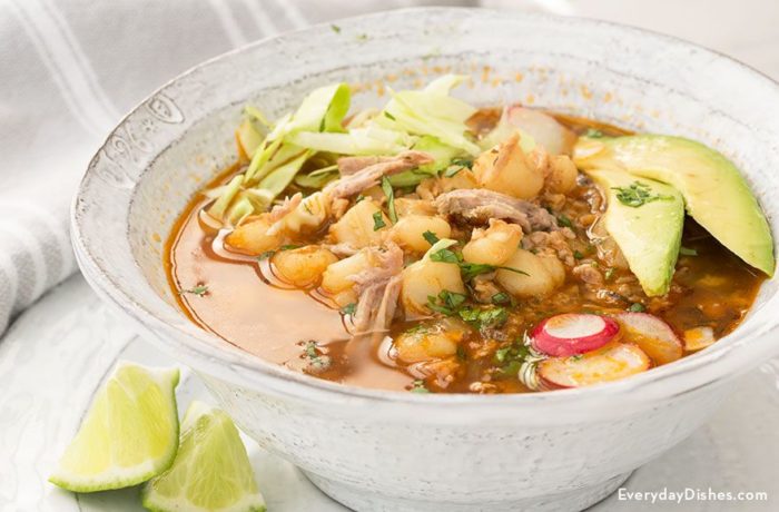 A steamy bowl of slow cooker posole rojo, garnished with lime.