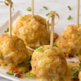 A platter of chicken sausage meatballs, garnished with green onion and speared with toothpicks.
