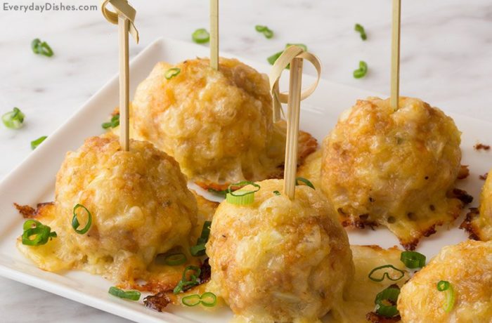 A platter of chicken sausage meatballs, garnished with green onion and speared with toothpicks.