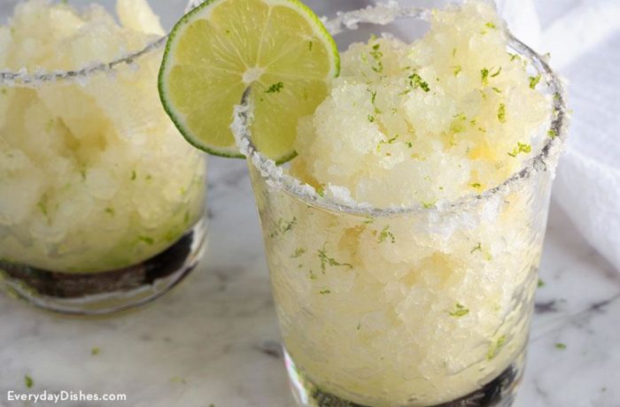Two glasses of delicious margarita granitas, rimmed with salt and garnished with lime.
