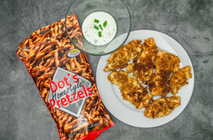 A plate of homemade chicken tenders, next to a bowl of dipping sauce and a bag of Dot's Pretzels, which were used as breading on the tenders.