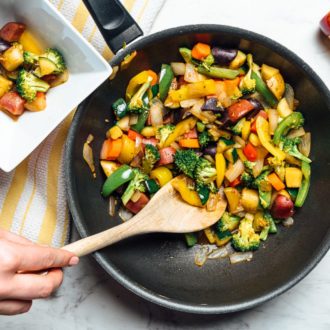 A Whole 30 vegan veggie stir fry, being served out of a skillet.