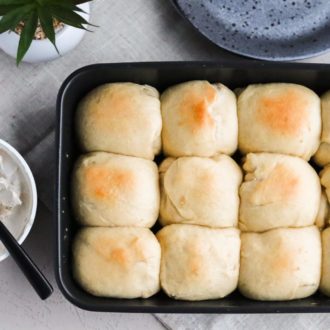 A pan of quick vegan dinner rolls, next to a container of vegan butter.