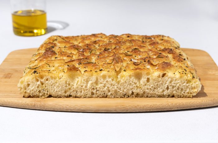 Freshly baked focaccia bread on a cutting board and ready to enjoy.