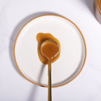 Delicious caramel made with brown sugar, in a spoon resting on a plate.