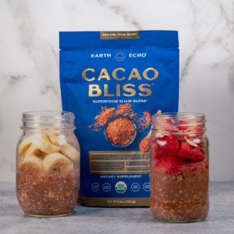 Two jars of overnight oats, made with Cacao Bliss, with strawberries and bananas as a garnish.