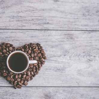 A mug of espresso, surrounded by a heart made of espresso beans.