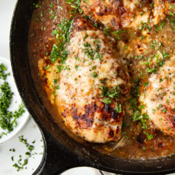 French onion chicken in a skillet, being cooked for a high-protein dinner that's good for weight loss.